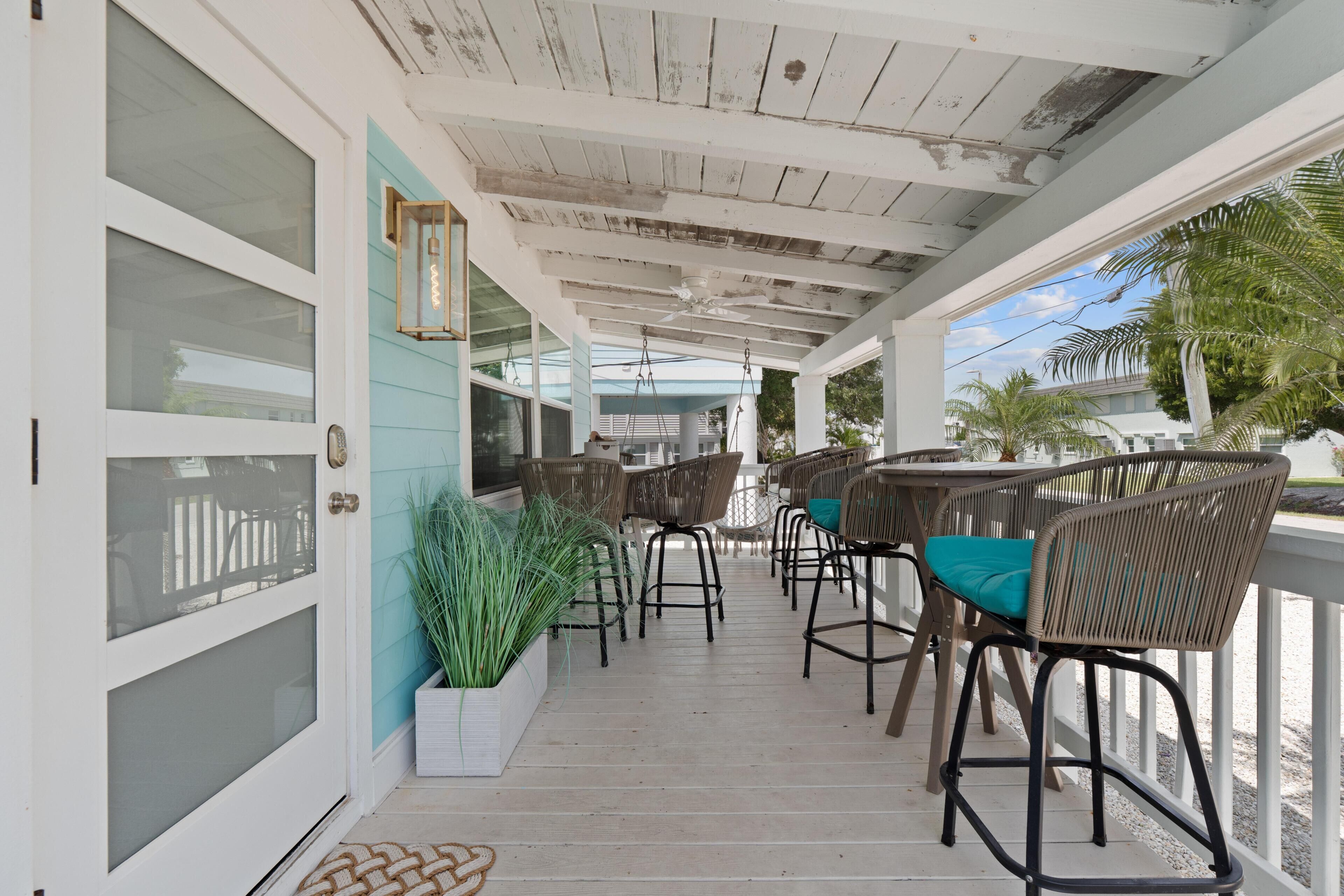 A covered porch with wicker furniture and a white door.