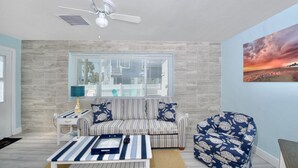A living room with a sofa, armchair, and coffee table, a ceiling fan, and a window with blinds. - MT Wind Swept #5 (Fort Myers Beach)