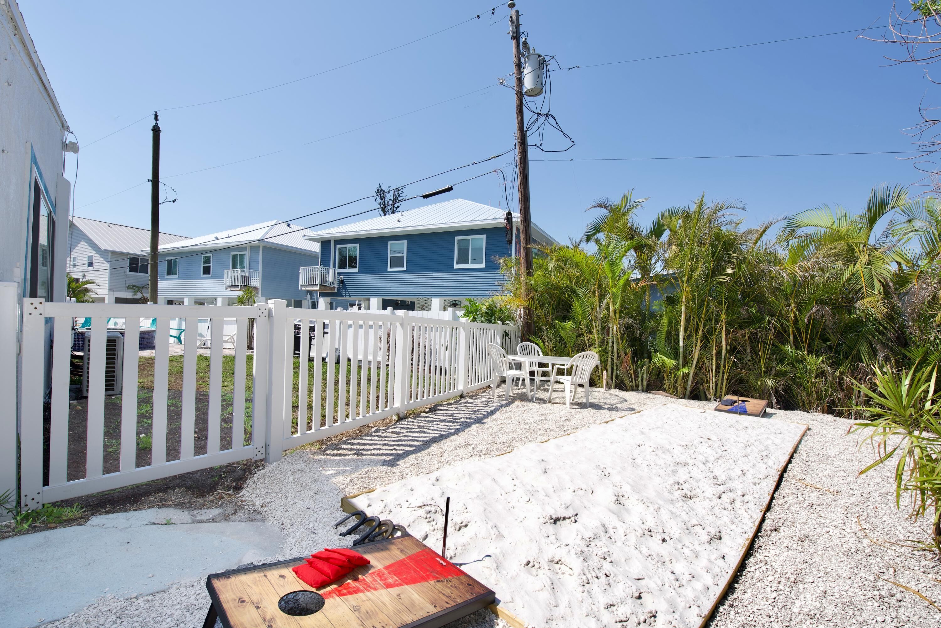 A residential area with a white picket fence, a blue house, and a wooden deck.