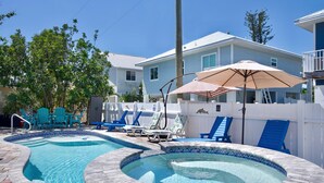 A swimming pool with lounge chairs and a hot tub, surrounded by a white fence and a house. - MT Wind Swept #5 (Fort Myers Beach)