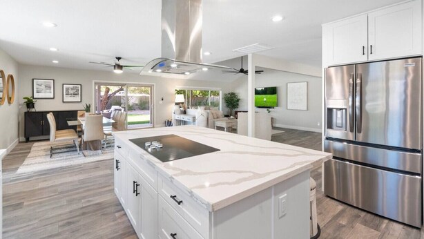 Una cocina moderna con una isla grande, electrodomésticos de acero inoxidable y un comedor con vistas al exterior.