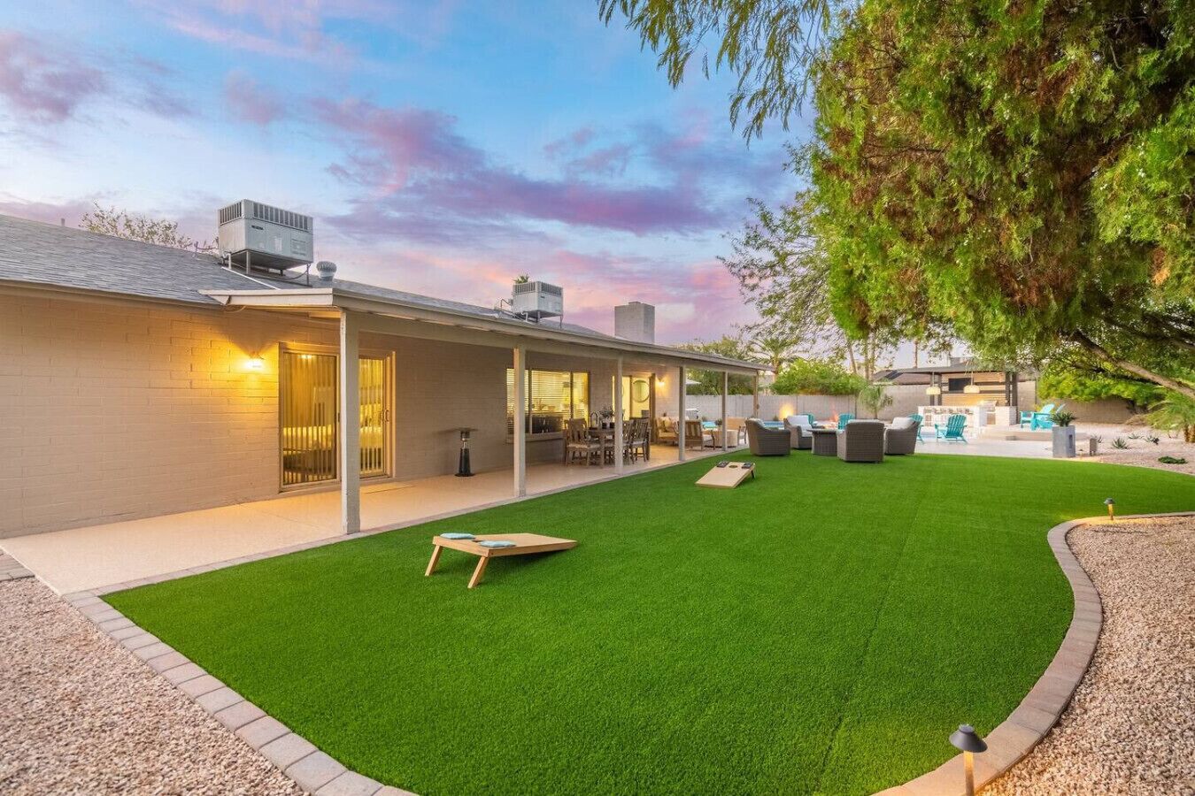 A modern house with a covered patio, a lawn, and outdoor furniture.