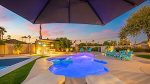 Un patio trasero con piscina, bañera de hidromasaje y mobiliario para exteriores.