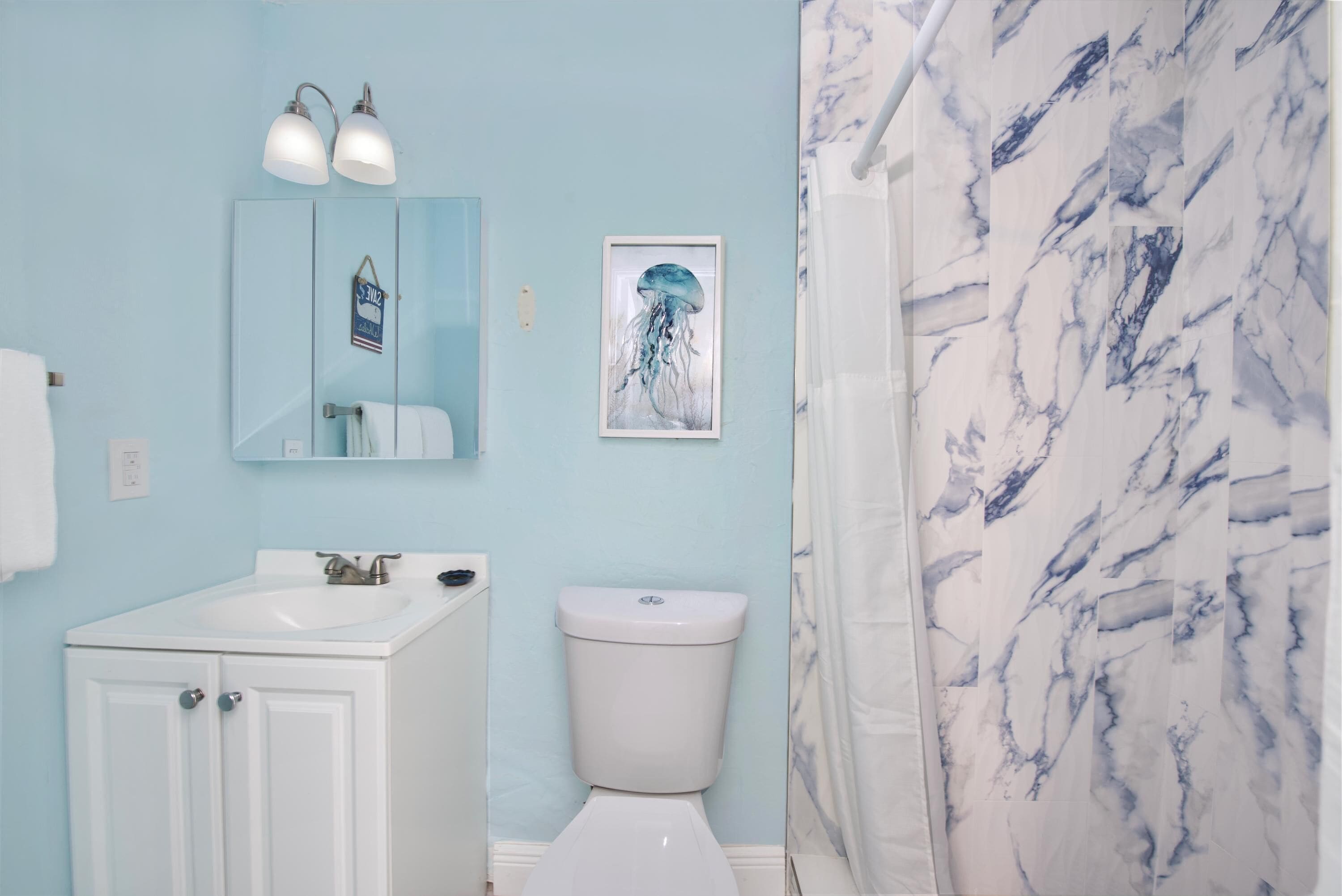 A bathroom with a white sink, a toilet, and a shower curtain with a marble pattern.