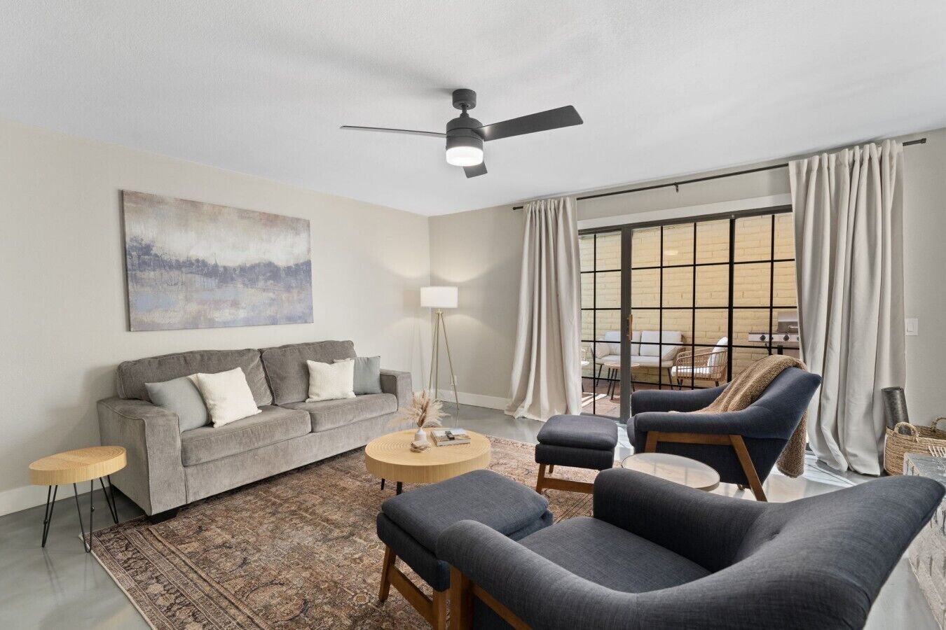 A living room with a grey sofa, a blue armchair, a round coffee table, and a floor lamp.