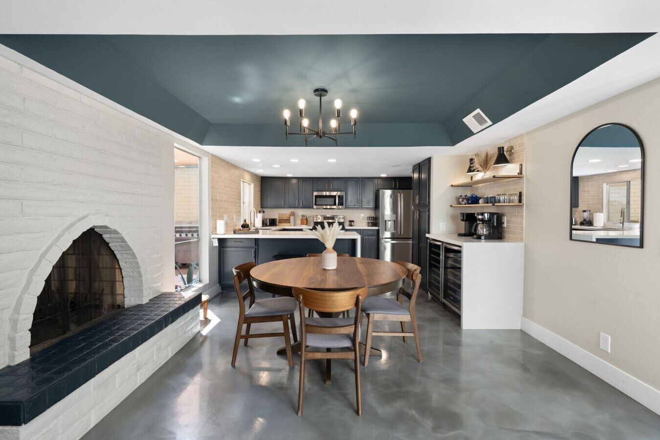 A modern kitchen with a central island, built-in appliances, and a dining area with a round table and chairs.