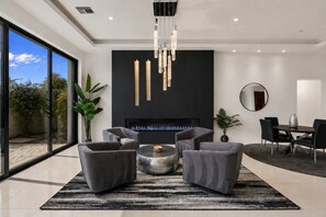 Ein modernes Wohnzimmer mit Kamin, grauen Sofas, einem Couchtisch und einem großen Fenster.