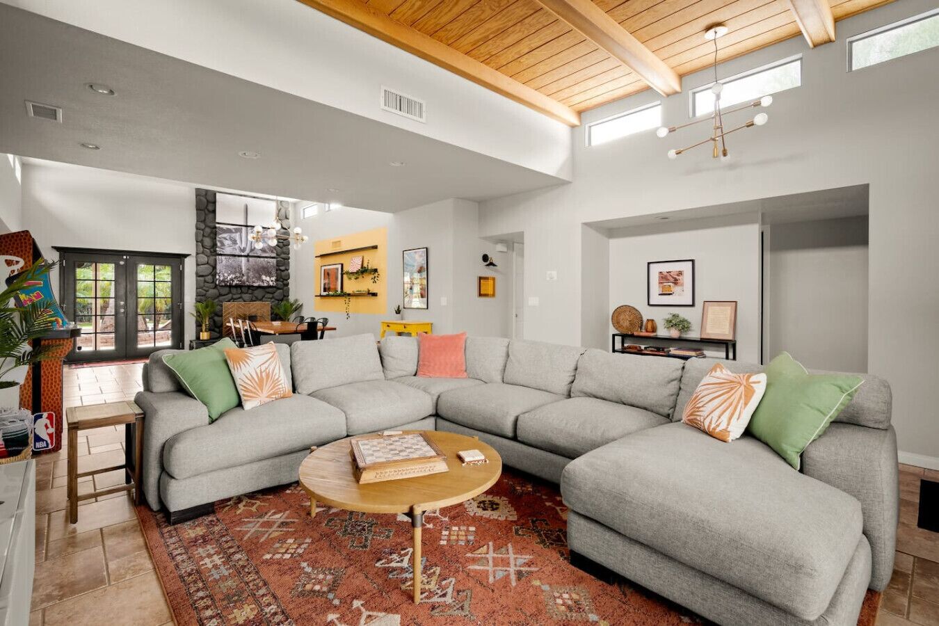 Amplio salón con un sofá seccional gris grande, una mesa de centro de madera y una alfombra estampada.