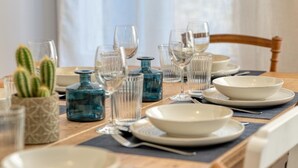 A dining table set with clear glassware, blue glass bottles, and white plates. - Perfect location! Quiet fisherman's cottage / terrace, bbq, elec. bikes.  (Trouville-sur-Mer)
