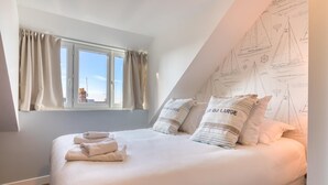A bedroom with a large bed, a window with curtains, and a wall with sailboat drawings. - Perfect location! Quiet fisherman's cottage / terrace, bbq, elec. bikes.  (Trouville-sur-Mer)