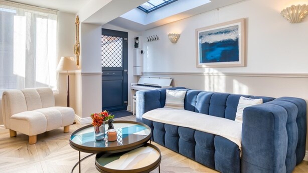 A modern living room with a blue sofa, a round glass coffee table, and a piano in the background. - Perfect location! Quiet fisherman's cottage / terrace, bbq, elec. bikes.  (Trouville-sur-Mer)