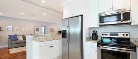 A modern kitchen with white cabinets, stainless steel appliances, a granite countertop, and a built-in oven.