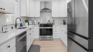 Une cuisine moderne avec des meubles blancs, des appareils en acier inoxydable et un four encastré.