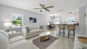 Uma sala de estar moderna com um sofá, mesa de centro e uma área de jantar com cadeiras e uma mesa.