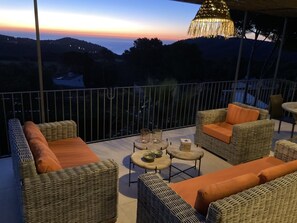 A balcony with wicker furniture, a table, and a hanging light fixture.