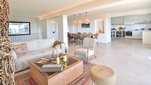 A modern living room with a sofa, coffee table, and dining area. - Casa Las Rocas (Begur) (Begur)