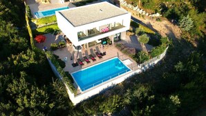 A modern two-story house with a swimming pool, outdoor seating, and a well-maintained garden.