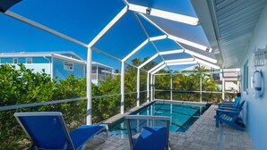 A covered outdoor swimming pool with blue chairs and a clear view of the surrounding buildings. - Miramar Palms (Fort Myers Beach)