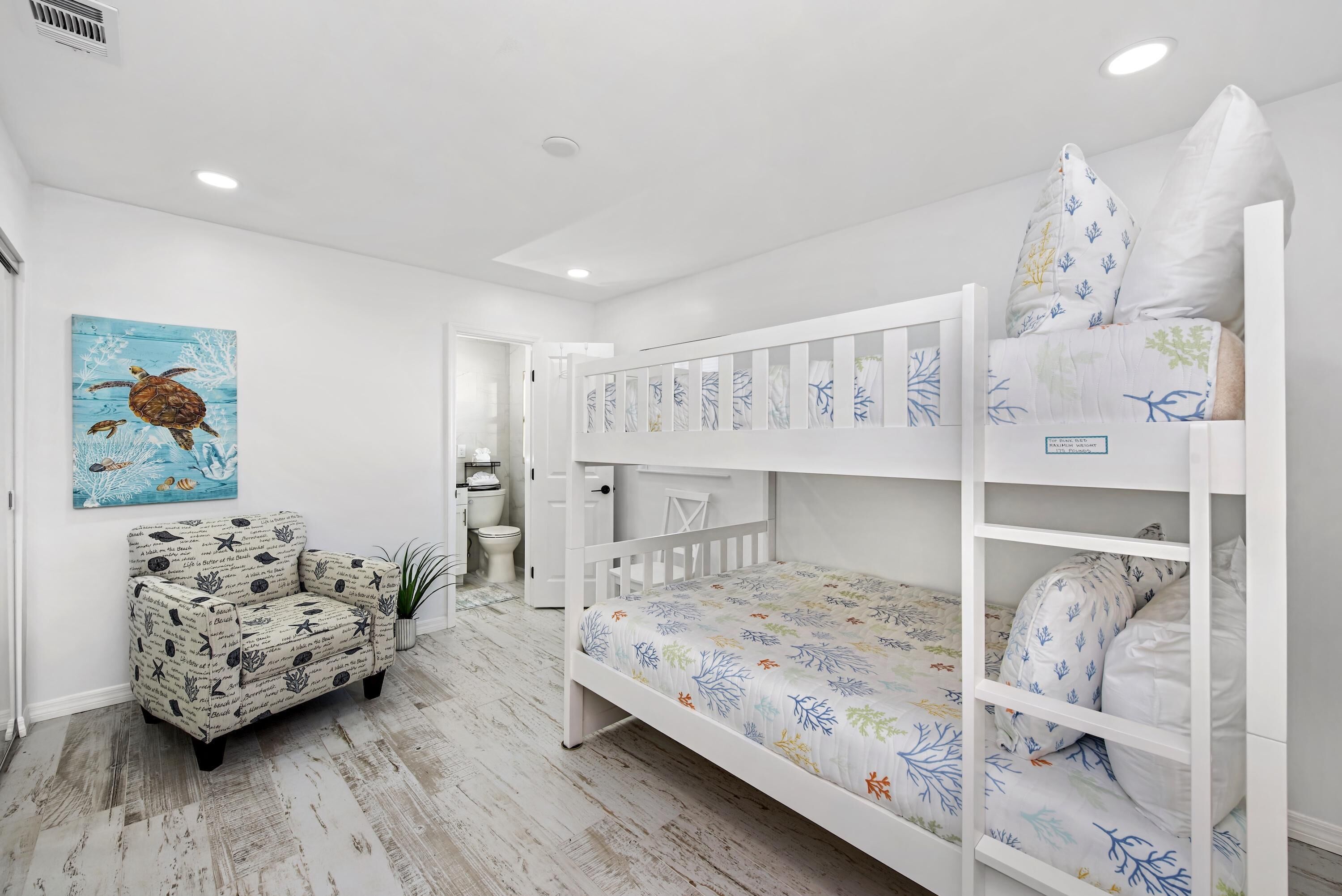 Habitación infantil con literas, un sofá y un cuadro de una tortuga.