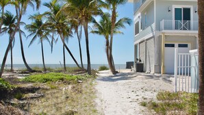 A beachfront property with a sandy path leading to a white building with a balcony. - Coconut Villa A (Fort Myers Beach)
