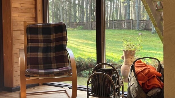 Une chaise en bois avec un coussin à carreaux, un panier en osier et un vase avec une plante, le tout posé sur un rebord de fenêtre.