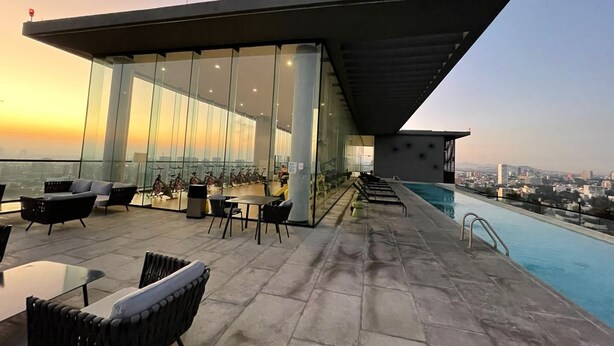 A rooftop terrace with a swimming pool, seating area, and a view of the city skyline at sunset. - Luxury 3BR Condo in Colonia Americana Pool, Gym & Workspace (Ladron de Guevara)