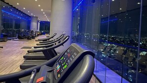 A gym with treadmills and exercise equipment, large windows with a city view, and a modern interior design. - Luxury 3BR Condo in Colonia Americana Pool, Gym & Workspace (Ladron de Guevara)