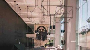 A modern living room with a sofa, coffee table, and hanging light fixtures. - Luxury 3BR Condo in Colonia Americana Pool, Gym & Workspace (Ladron de Guevara)