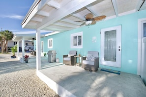 Relax in this serene outdoor space with a wicker chair, table, and ceiling fan.