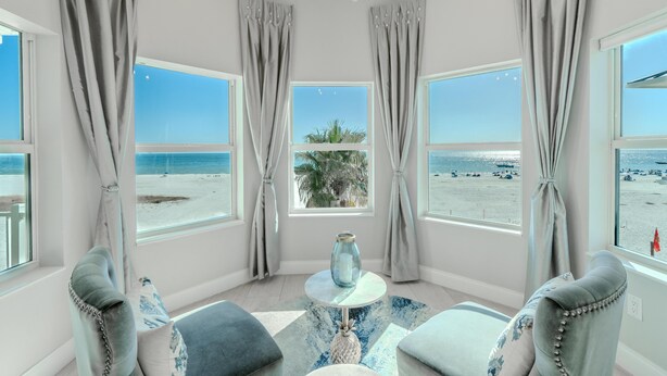 A room with large windows, a round table, and two armchairs, overlooking a beach. - White Sugar Sands (Fort Myers Beach)