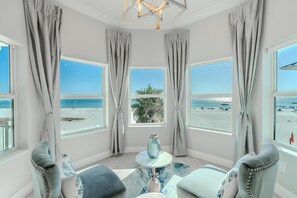 A room with large windows, a round table, and two armchairs, overlooking a beach. - White Sugar Sands (Fort Myers Beach)