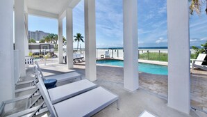 A poolside area with white lounge chairs, a pool, and a view of the ocean. - White Sugar Sands (Fort Myers Beach)