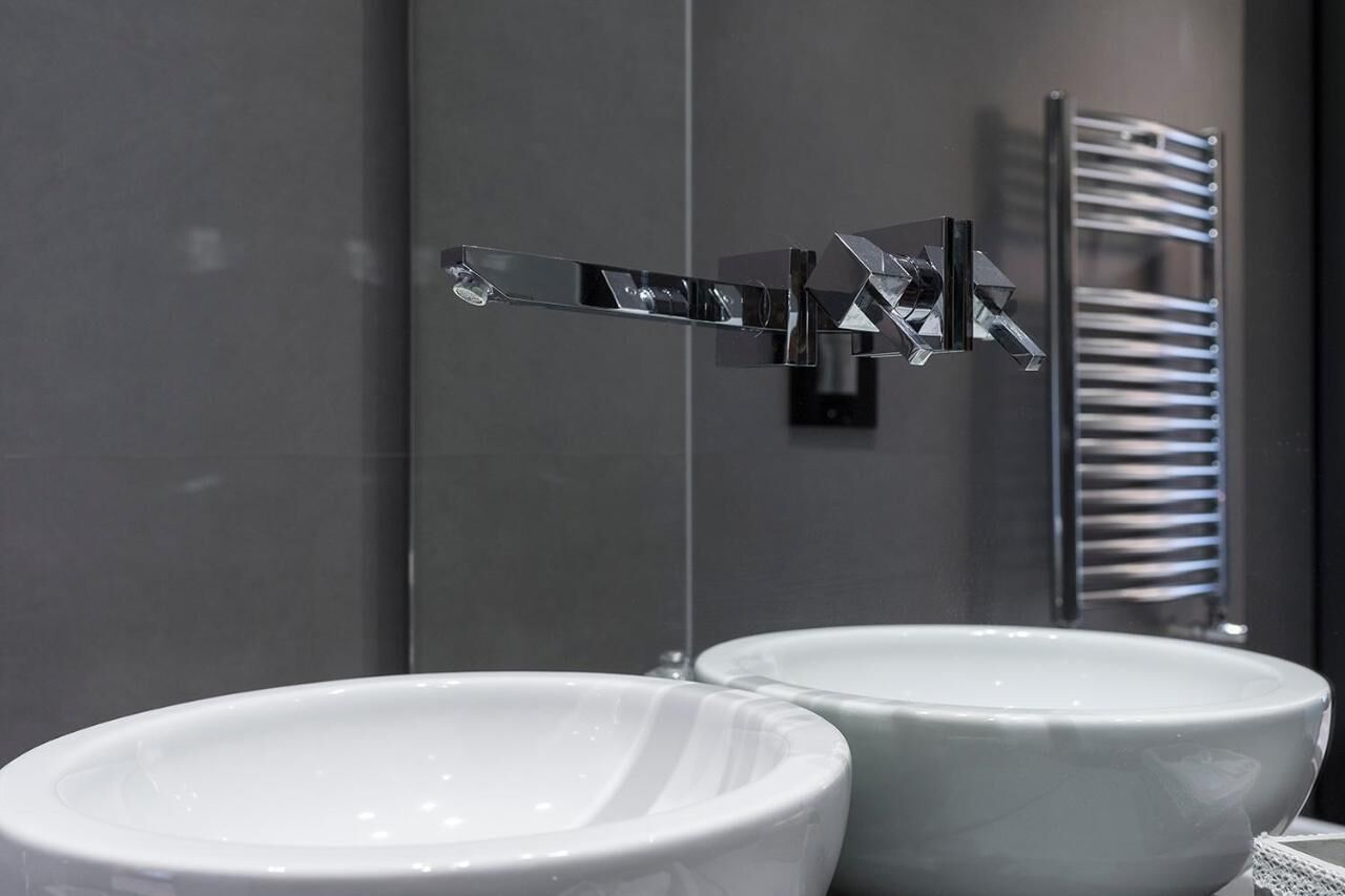 A modern bathroom with two white ceramic sinks and a chrome faucet.