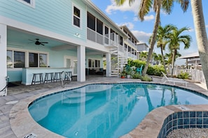 A swimming pool with a covered deck area, a bar, and outdoor seating. - Harborside on Palermo (Fort Myers Beach)