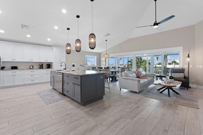 A spacious kitchen with a central island, white cabinetry, and modern pendant lighting. - Harborside on Palermo (Fort Myers Beach)