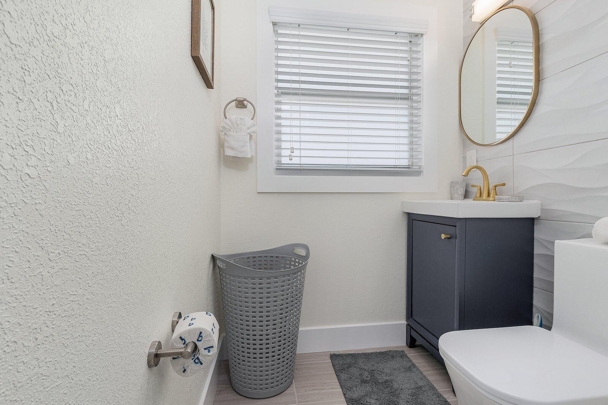 Une salle de bain avec des toilettes, un lavabo et une fenêtre équipée de stores.