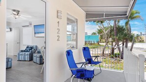 Habitación de hotel moderna con balcón, televisión y vistas a palmeras.