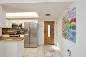 Kitchen features stainless steel appliances, a granite countertop, and a wooden door leading to another room.