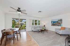 Relax in this stylish living room with a dining area, sofa, and armchair, offering a view of the outdoors.