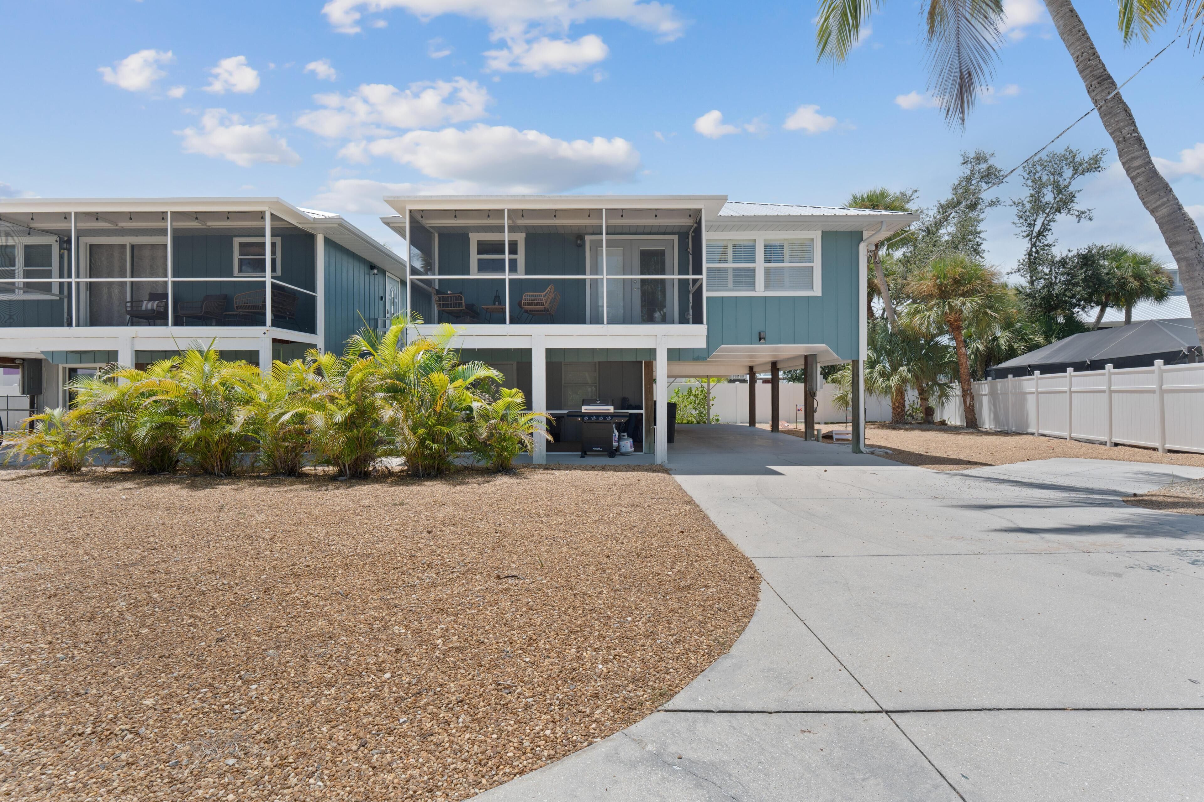 A two-story house with a covered patio and a gravel driveway.