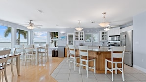 Una cocina moderna con armarios blancos, una isla central y vista al agua.