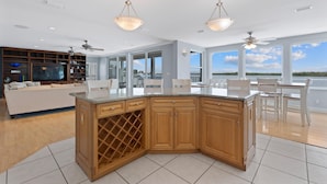 Una cocina moderna con una isla grande, estante empotrado para vinos y un comedor con vistas.