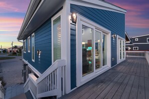 A two-story building with a deck, large windows, and a blue exterior. - Flip Flops Forever (Fort Myers Beach)