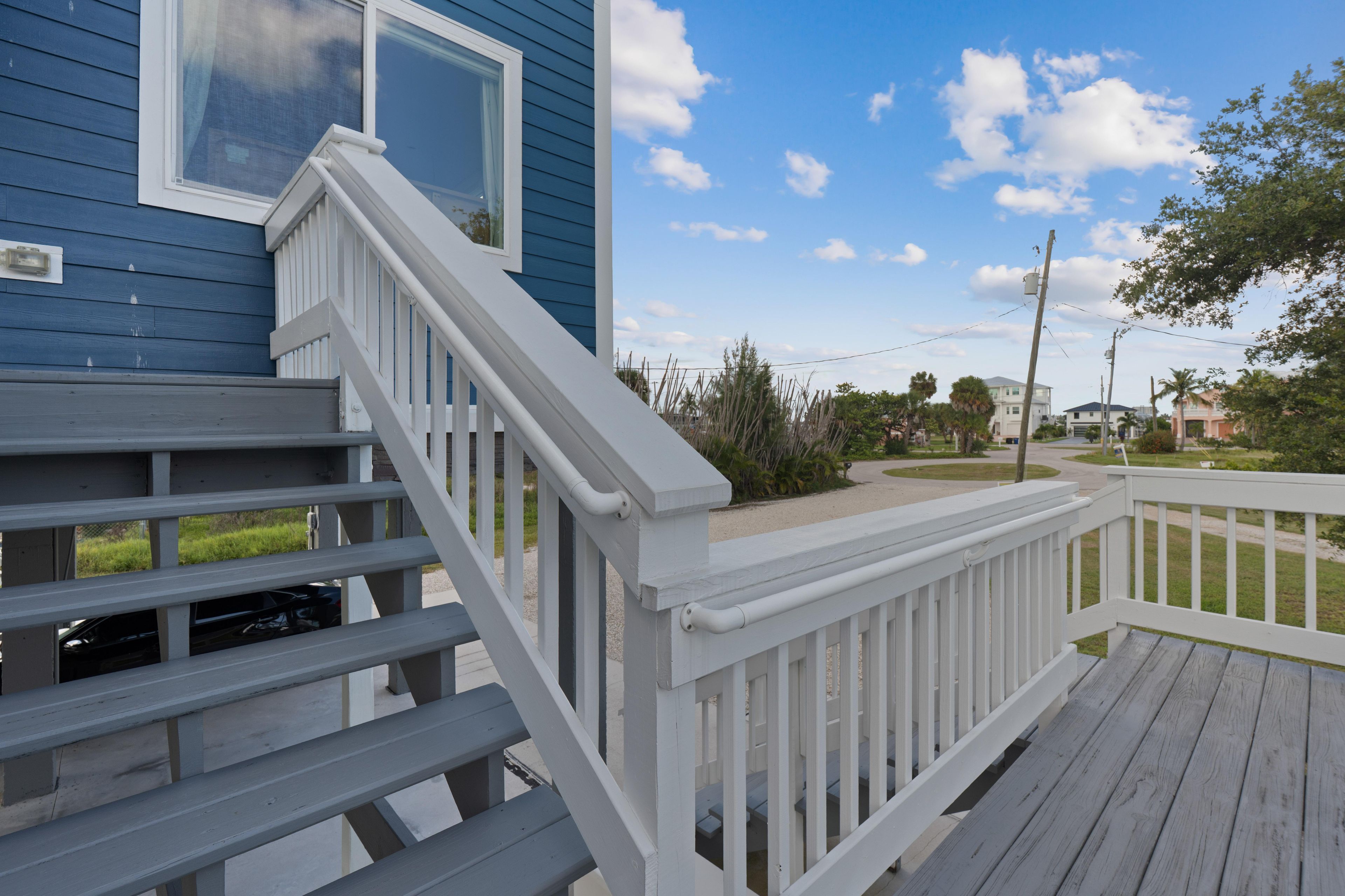 A residential property with a wooden deck, a staircase, and a clear view of the neighborhood.