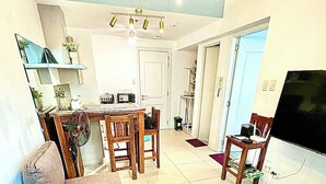 Una sala de estar con sofá, televisión y comedor con sillas y mesa.