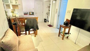 Una sala de estar con un sofá, un televisor y un comedor con una mesa y sillas.