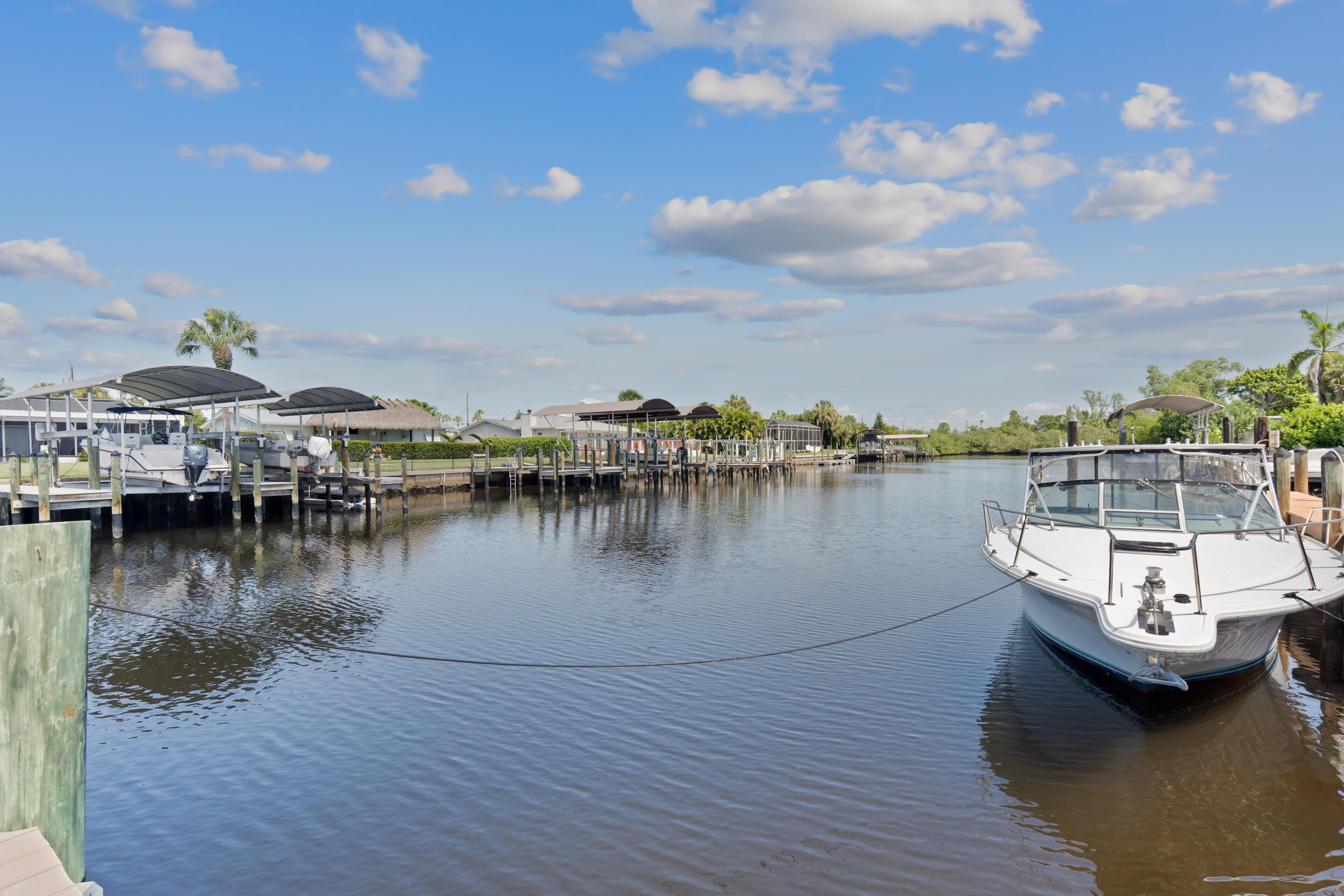 A marina with boats docked, a dock with a covered area, and a clear sky.