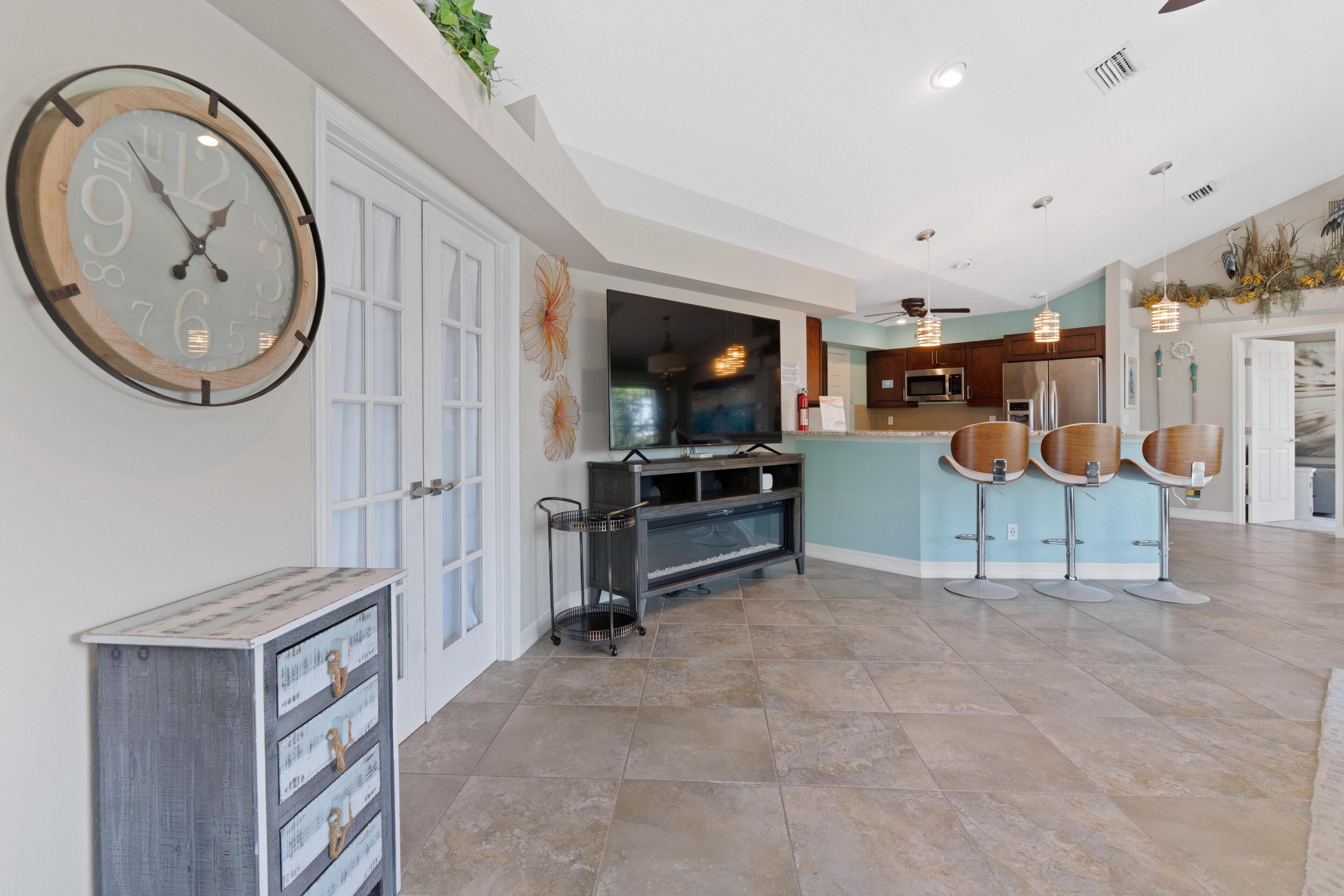 A spacious kitchen with a large clock, a dining area with bar stools, and a modern interior design.