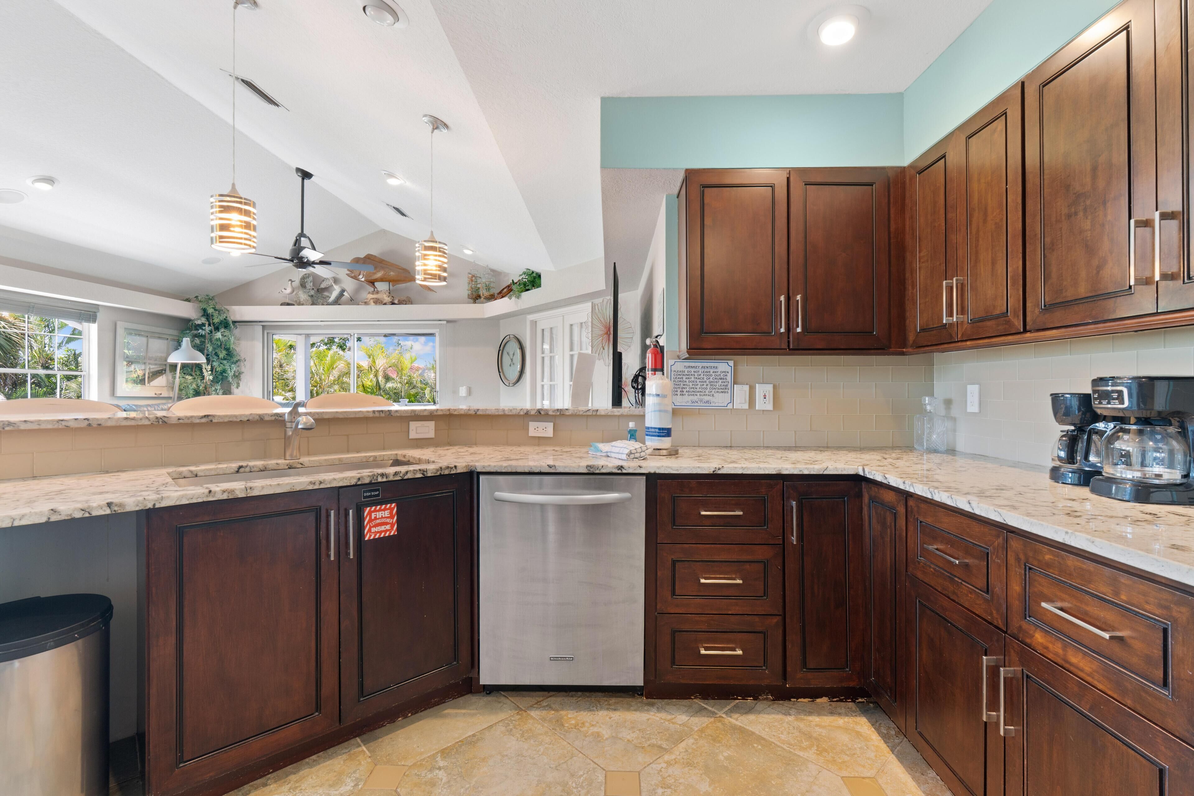 A modern kitchen with dark wood cabinets, a stainless steel dishwasher, and a marble countertop.