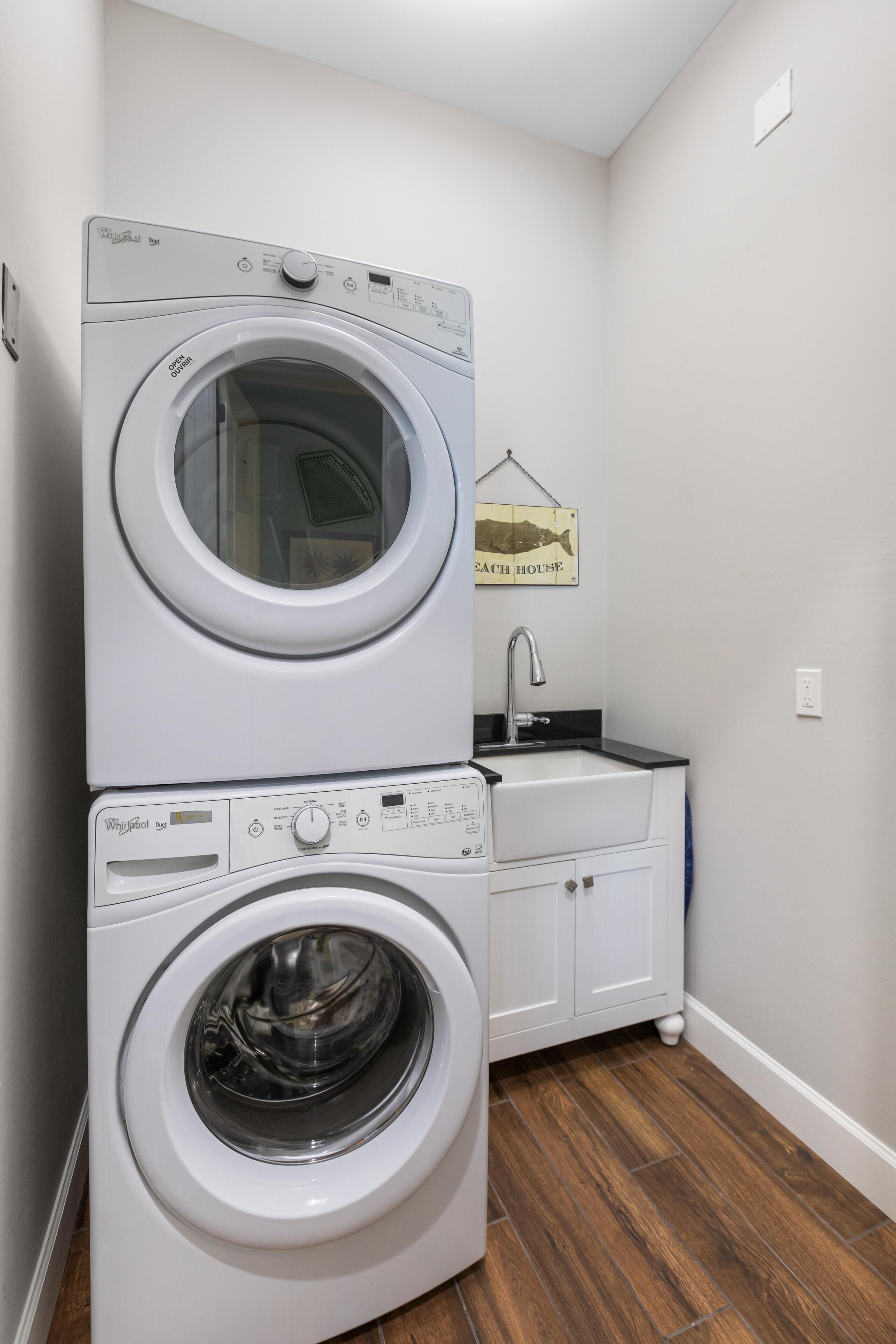 A laundry area with two stacked washers and a sink.